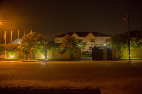 a street at night with a house and palm trees at Magnolia lodge in Accra
