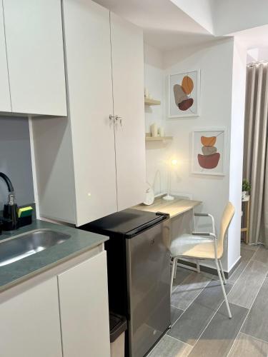 a kitchen with white cabinets and a desk with a chair at BIT by Simple stay in Medellín