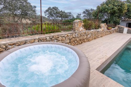 a swimming pool with a hot tub in a backyard at Cottage with Jacuzzi, Sierra Norte, close to Seville in Guillena