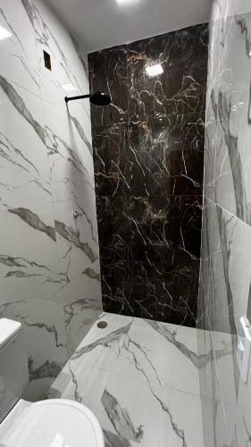 a bathroom with a marble shower and a toilet at Apartamento no Centro da Cidade in Parauapebas