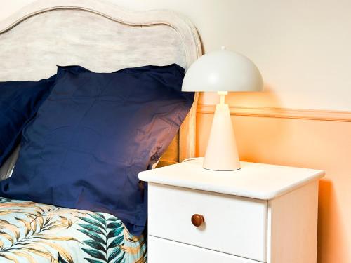 a bed with a white nightstand with a lamp on it at Gite d'exception au Château in Le Fief-Sauvin