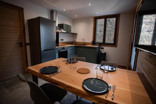 een keuken met een houten tafel met glazen erop bij Appartement dans le Mercantour - accès PMR - in Saint-Étienne-de-Tinée