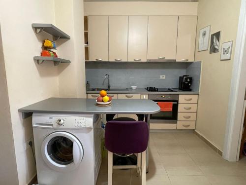 a kitchen with a washing machine with a bowl of fruit on a table at Sea-side apartment in Kavajë