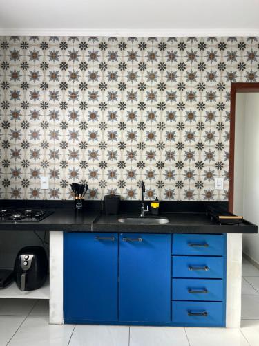 Una cocina con un fregadero azul y un papel pintado. en Thom's House, en Santa Teresa