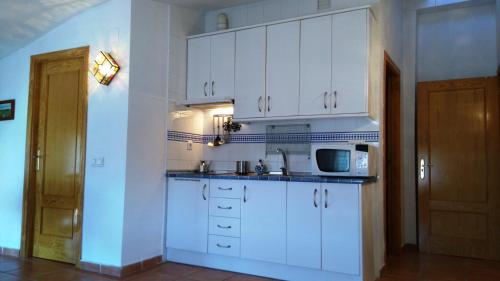 eine Küche mit weißen Schränken und einer Mikrowelle in der Unterkunft Un balcón al Guadalquivir in Hornos