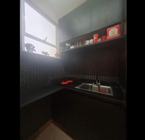a black kitchen with a sink and a window at Quarto e sala de luxo no centro histórico in Petrópolis