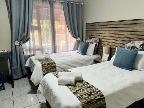 ヨハネスブルグにあるMap's View Guesthouseのベッドが2つと窓があるホテルの部屋