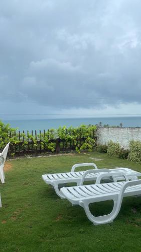 a row of white lounge chairs sitting on the grass at Casa Vila lagoinha in Lagoinha