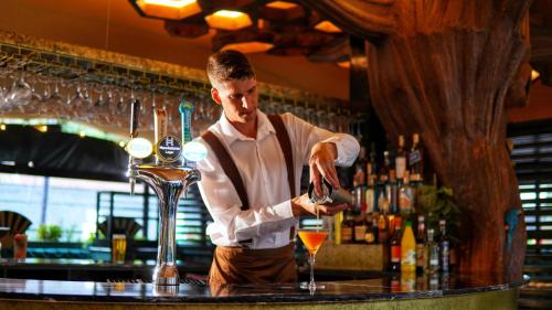 a bartender making a drink at a bar at Grovefield House Hotel in Slough