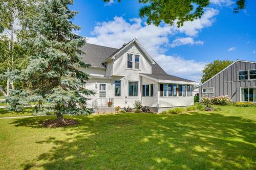a white house with a tree in the yard at Two Rivers Thiede House - Walk to Lake Michigan! in Two Rivers