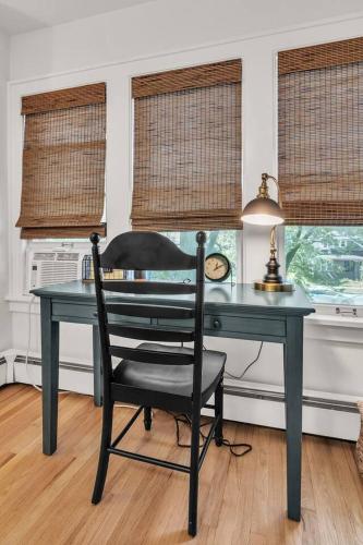 a desk with a chair in a room with windows at The Chateau de James by Granger Gardens in Ann Arbor