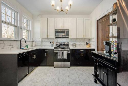 a kitchen with black and white appliances and a chandelier at The Chateau de James by Granger Gardens in Ann Arbor