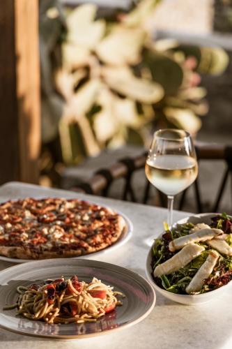 a table with three plates of food and a glass of wine at Mykonos Soul Luxury Suites in Agios Stefanos