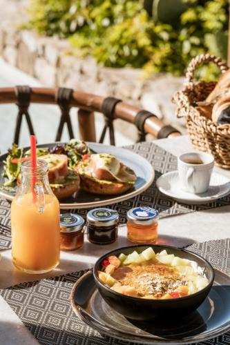 a table with plates of food and a bowl of orange juice at Mykonos Soul Luxury Suites in Agios Stefanos