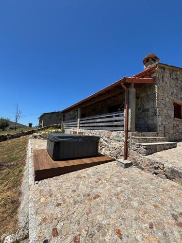 a stone building with a wooden deck with aburning at Casa da Tapada Santo Antonio in Branda de Santo António