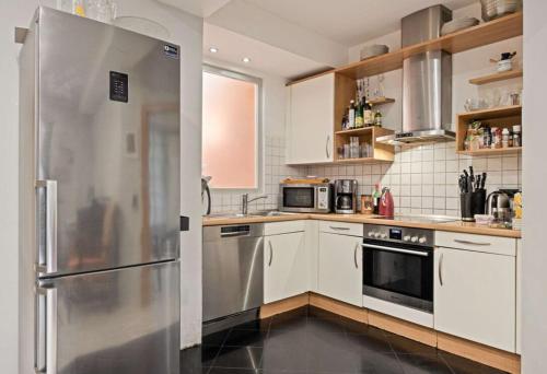 a kitchen with white cabinets and a stainless steel refrigerator at Comfort in Hürth with pool and fireplace in Hürth
