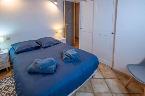 a bedroom with a blue bed with towels on it at La Canotière in Saint-Georges-dʼOléron