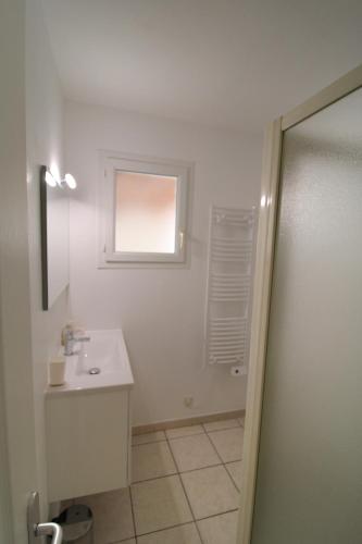 un bagno bianco con lavandino e finestra di Villa l'Oranger a Sigean