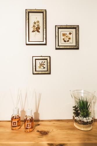 three vases on a wooden table with pictures on the wall at Le Coste in Villetta Barrea