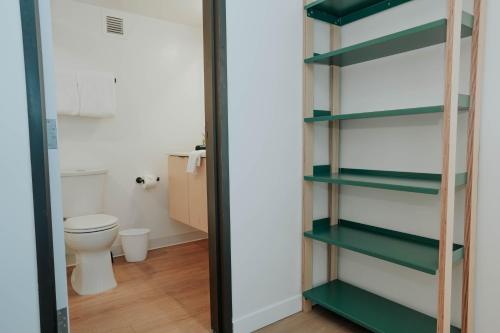 Un baño con inodoro y estantes verdes. en Downtown Cozy Vista DT Gym Free Parking, en Salt Lake City