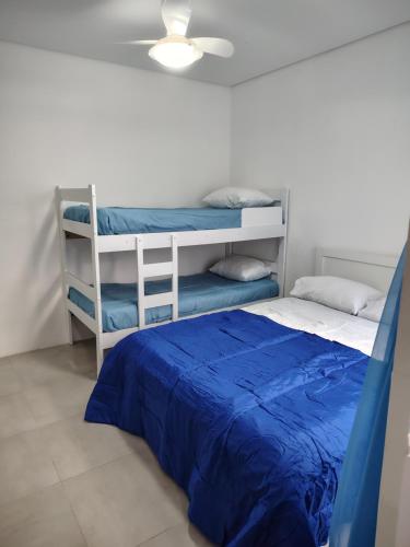 1 Schlafzimmer mit 2 Etagenbetten und einem blauen Bett in der Unterkunft Casa do Sol III in Peruíbe
