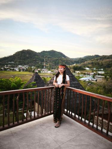 a woman standing on a balcony with mountains in the background at Golo Pada Villa Labuan Bajo by ABM in Nggorang