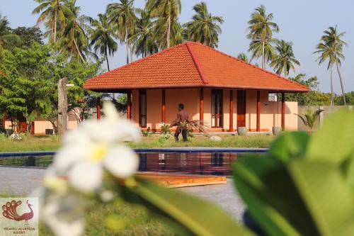une maison avec un toit orange à côté d'une piscine dans l'établissement Nilaveli Ayurveda Resort, à Nilaveli