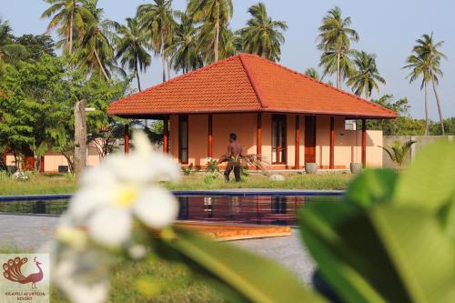 a house with an orange roof next to a pool at Nilaveli Ayurveda Resort in Nilaveli