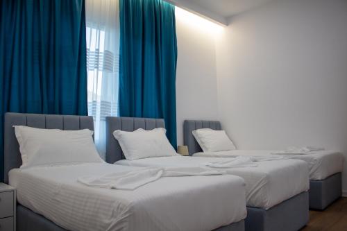 two beds in a room with blue curtains at The Horizon in Berat