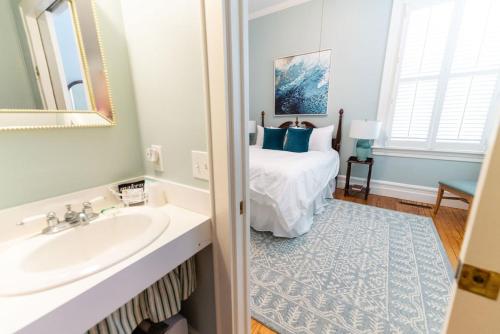 a bathroom with a sink and a bed at The Edenton Collection-Captain's Quarters Inn in Edenton