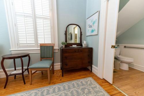 a bathroom with a table and a chair and a mirror at The Edenton Collection-Captain's Quarters Inn in Edenton