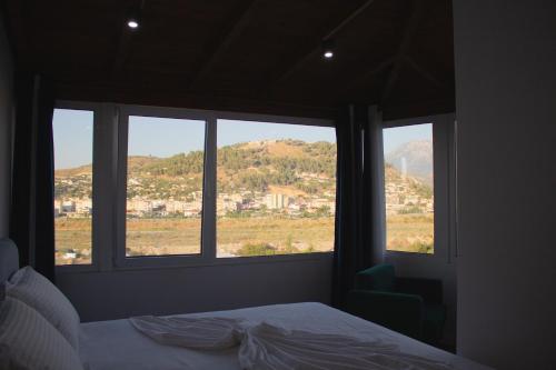 a bedroom with a bed and two windows with a view at The Horizon in Berat