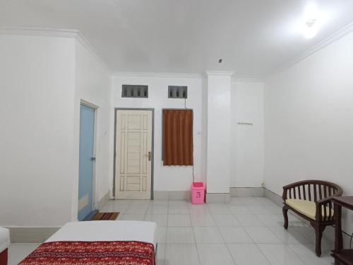 a bedroom with a bed and a chair and a door at Hotel STIPRAM Kaliurang Yogyakarta in Kaliurang