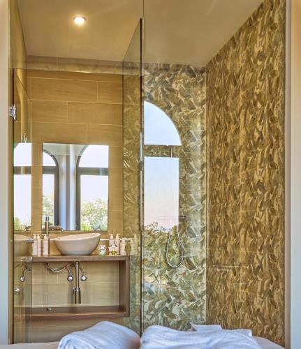 a bathroom with a shower with a sink and a mirror at Hotel Rural Palacio Haza de la Concepción in Malpartida de Plasencia