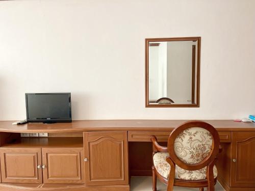 a desk with a tv and a mirror and a chair at Naya Park View Hotel in Ban Non Muang