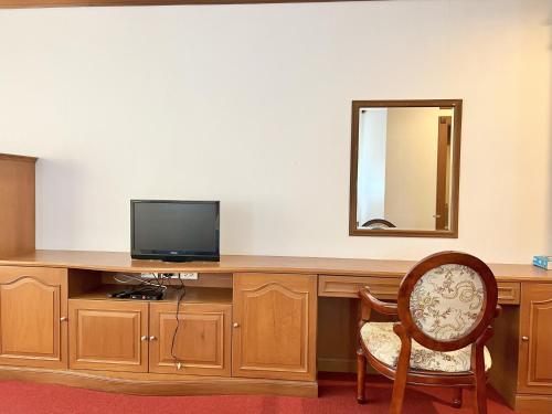 a room with a desk with a television and a chair at Naya Park View Hotel in Ban Non Muang