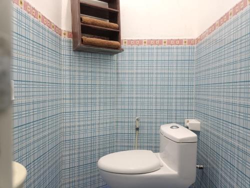 a bathroom with a toilet and blue tiled walls at Hotel STIPRAM Kaliurang Yogyakarta in Kaliurang