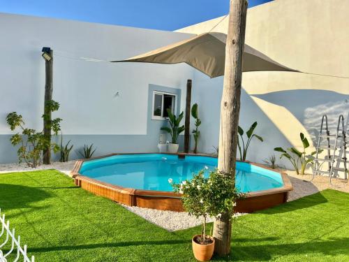 a swimming pool in a yard with an umbrella at REFUGIO by Stay in Alentejo in São Luis