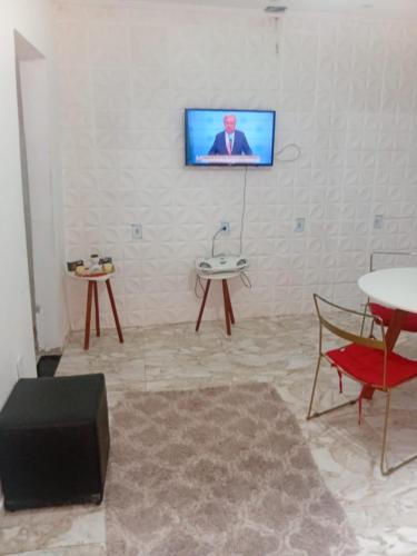 a living room with a tv on a white wall at Recanto das Águias in Maricá