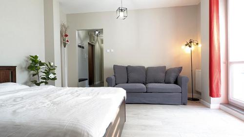 a bedroom with a bed and a couch at Ursus Pleasant Apartment by BookingHost in Warsaw