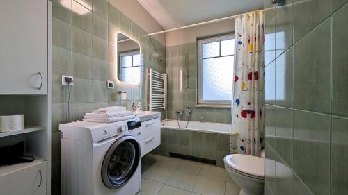a bathroom with a washing machine and a sink at Ursus Pleasant Apartment by BookingHost in Warsaw
