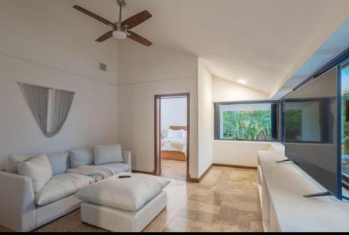 a living room with a white couch and a ceiling fan at Casa Playa Cozumel - Luxury Beachfront Villa in Cozumel