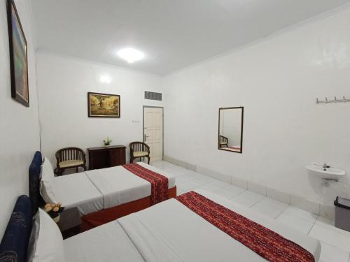 a hotel room with two beds and a sink at Hotel STIPRAM Kaliurang Yogyakarta in Kaliurang