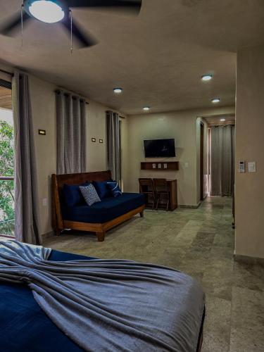 a bedroom with a bed and a couch and a desk at Loft Pelicano - Santuario Apartments in Chemuyil