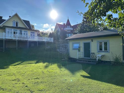 a house in a yard with the sun behind it at Small Seaside Cottage in Saltsjöbaden
