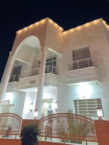 a large white building with a porch at night at Airport Villa Amman in Amman