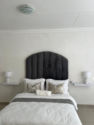 a bedroom with a large bed with a black headboard at Haven Hide Self Catering in Windhoek