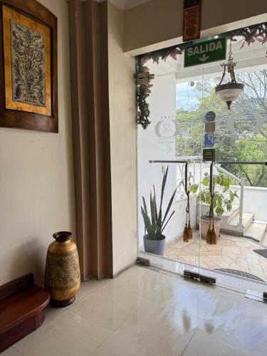 a lobby with a glass door with a vase on the floor at Hotel Jardines del Rio in Loja