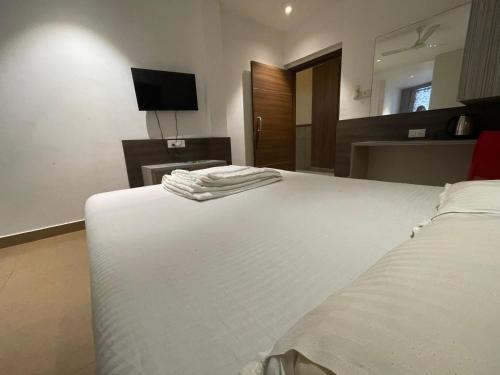 a bedroom with a white bed and a television at Shri Sai Palace in Udupi