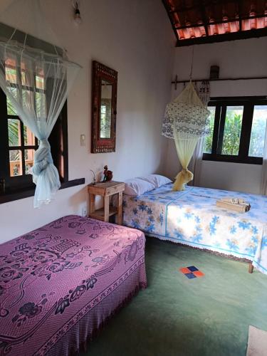 a bedroom with two beds in a room with windows at Boipeba Stay in Ilha de Boipeba